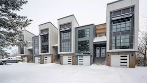 En modern byggnad med flera våningar, stora fönster och en garageuppfart.