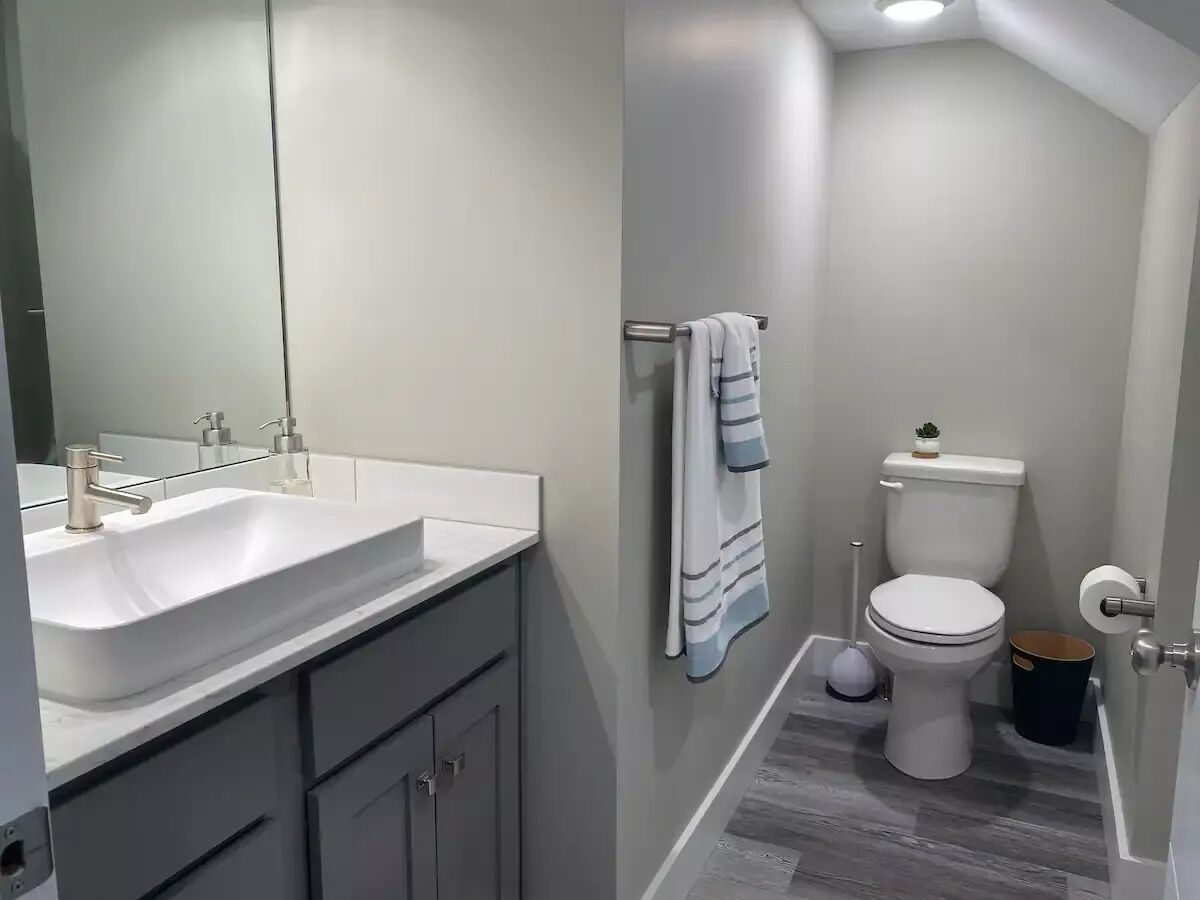 Une salle de bain moderne avec un lavabo blanc, un miroir et des toilettes.