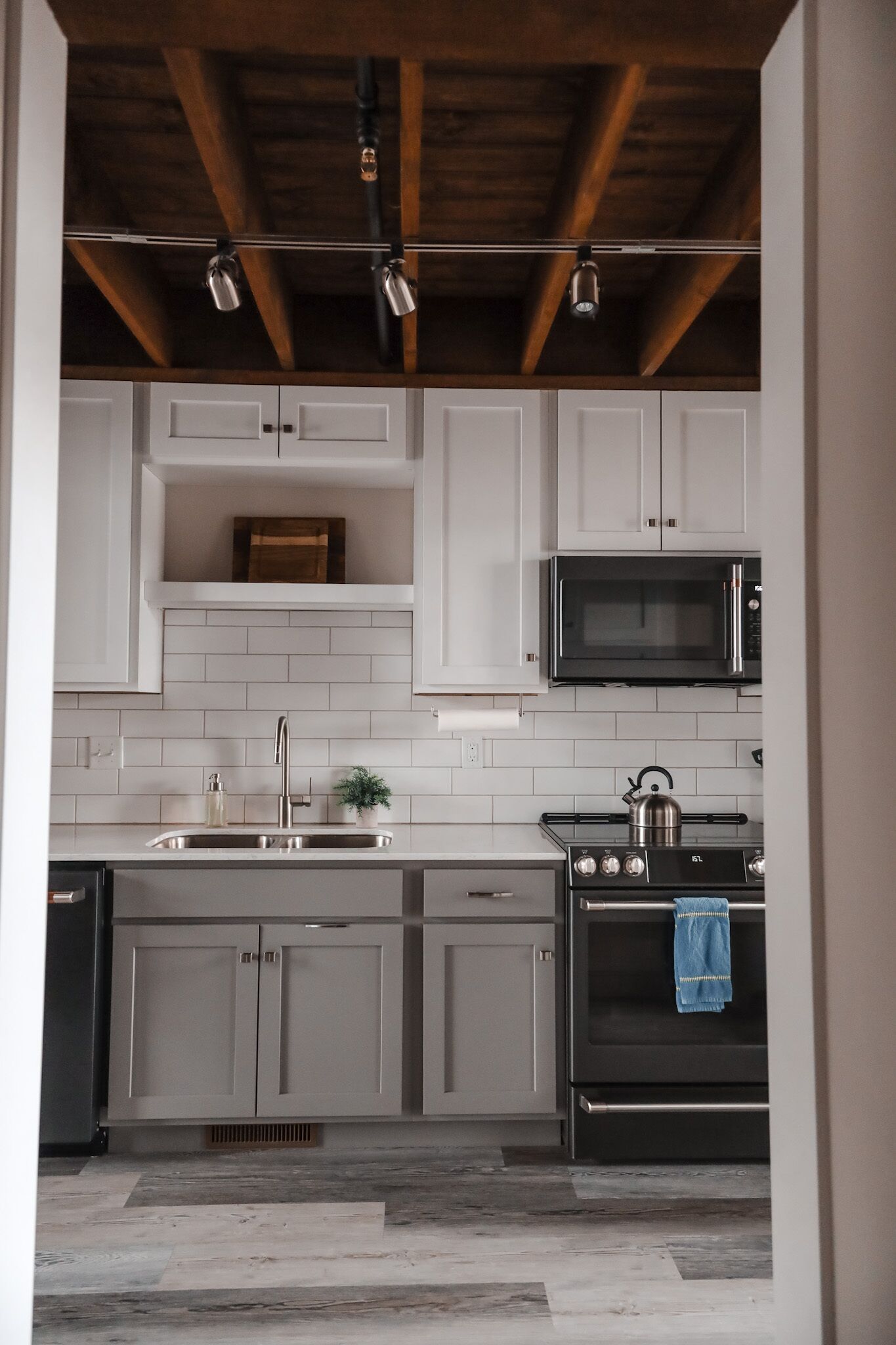 A modern kitchen with white cabinets, a stainless steel sink, a microwave, and an oven.
