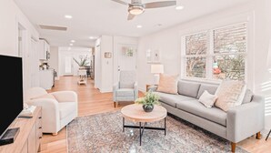 Una sala moderna con un sofá, sillones, una mesita de centro y un televisor.