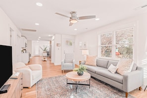 A modern living room with a sofa, armchairs, a coffee table, and a TV.