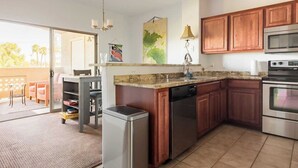 A modern kitchen with wooden cabinets, stainless steel appliances, and a dining area with a table and chairs.