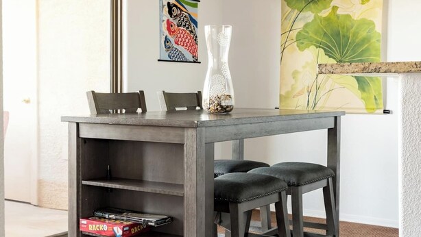 A dining area with a table, chairs, a chandelier, and artwork on the wall.