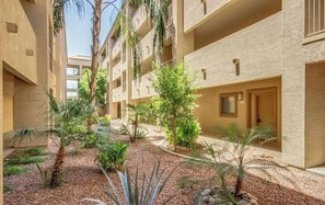 A courtyard with multiple-story buildings, palm trees, and a variety of shrubs.