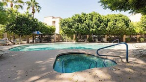 A swimming pool with a diving board, surrounded by trees and lounge chairs.
