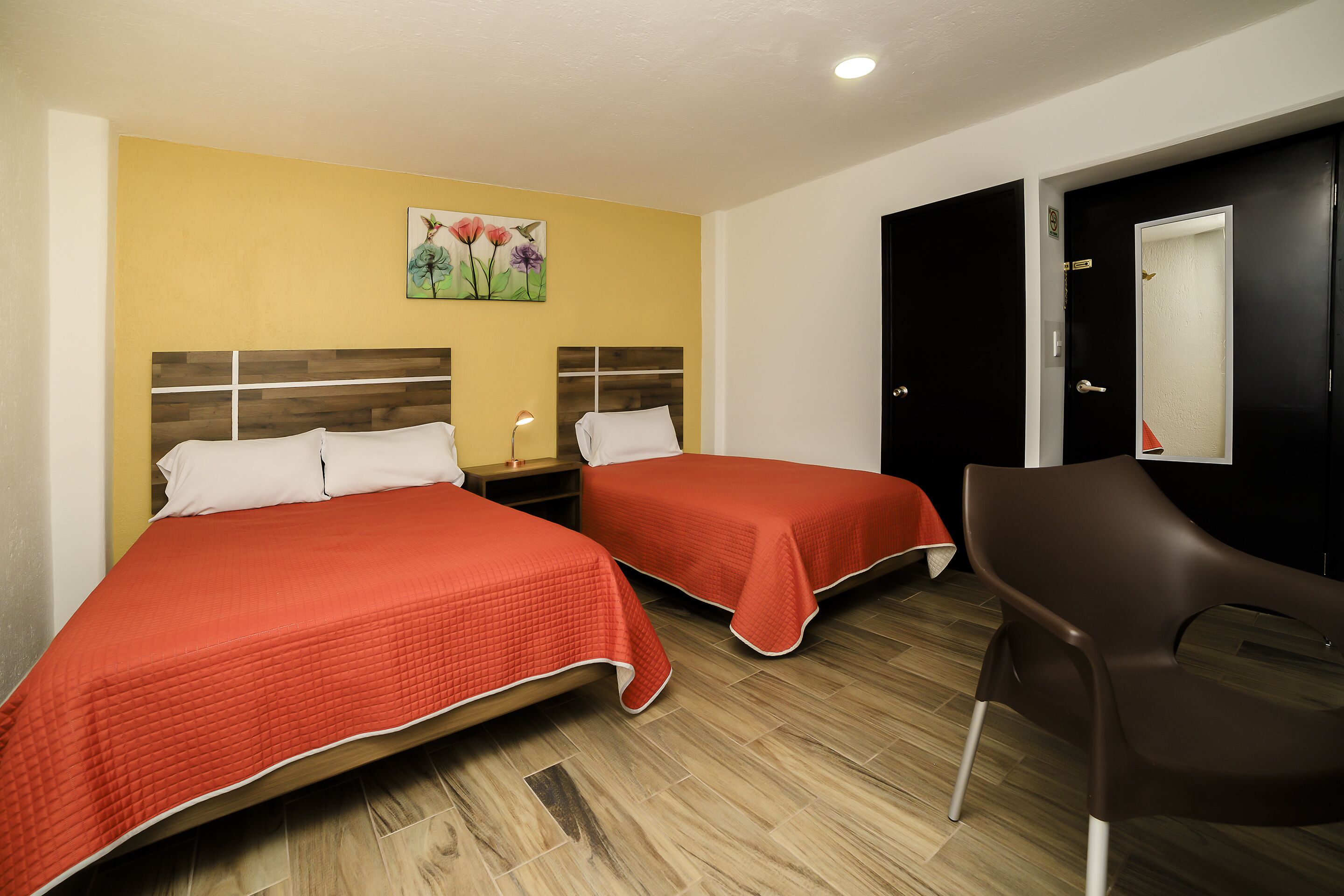 A hotel room with two beds, a desk, and a chair.