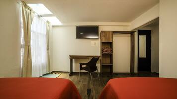 A hotel room with two beds, a desk, a chair, a TV, and a wardrobe.