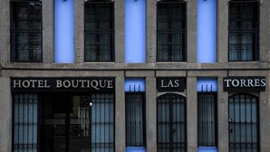 Eine Gebäudefassade mit drei Hotelschildern: HOTEL BOUTIQUE, LAS TORRES und einem teilweise sichtbaren dritten Schild.