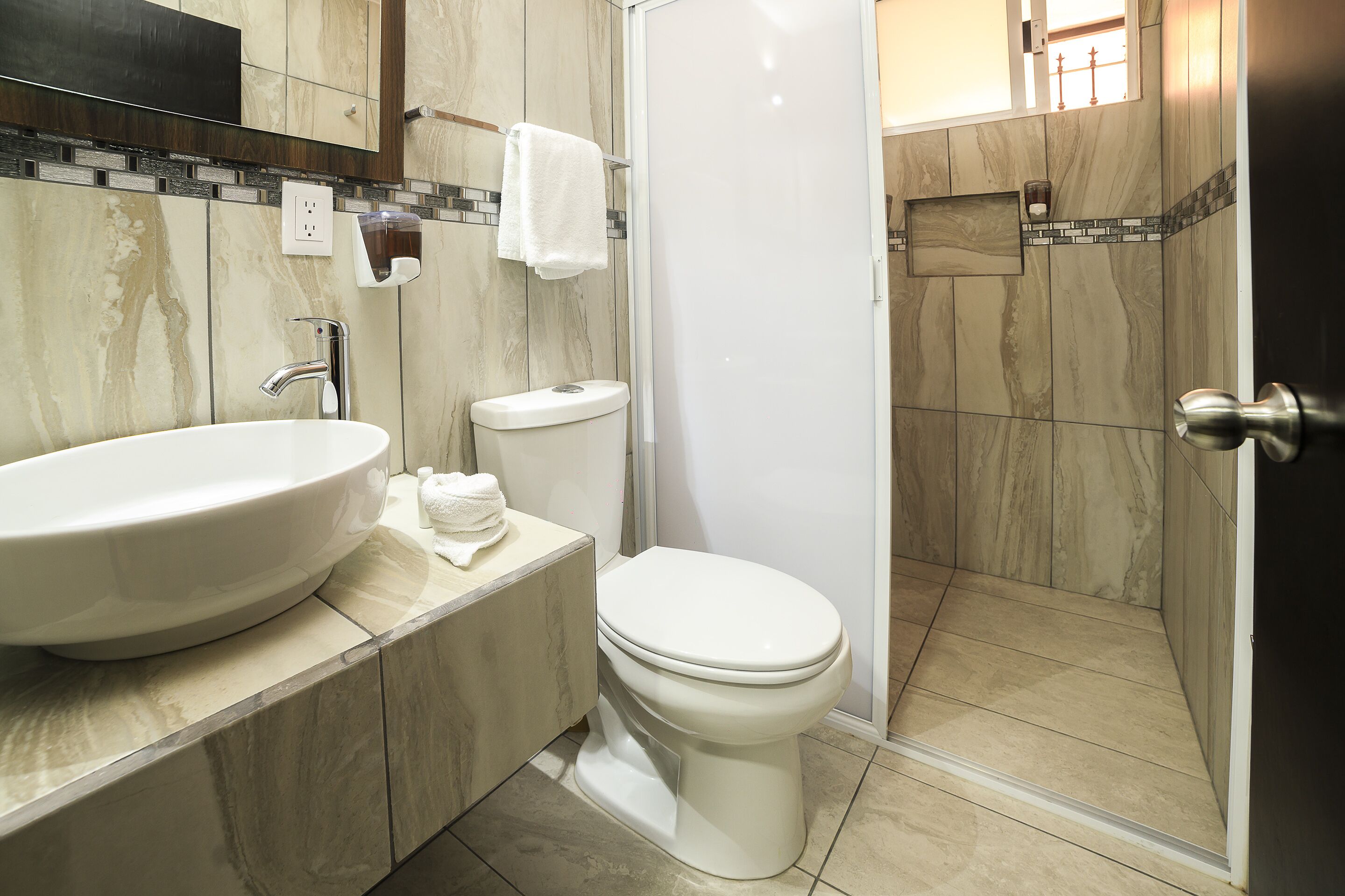 Un baño moderno con un lavamanos grande, inodoro y ducha.