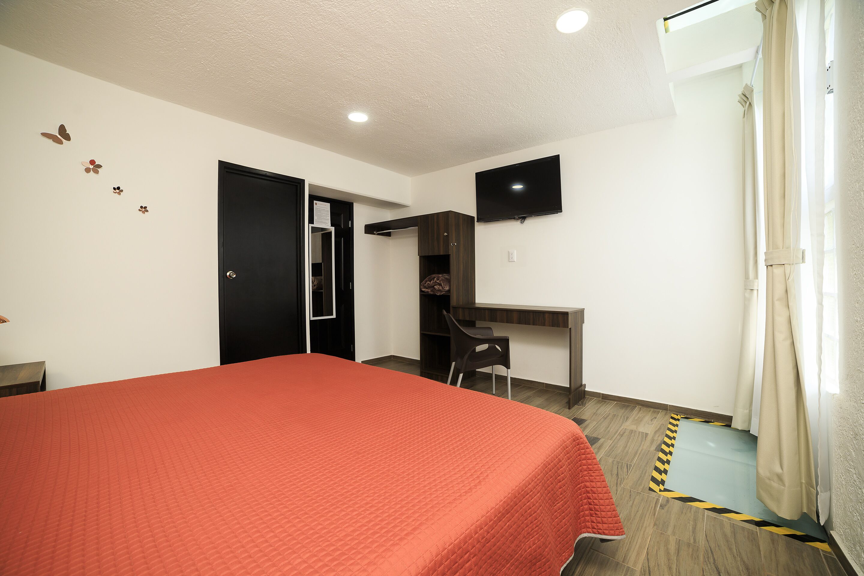 A bedroom with a bed, a desk, a chair, a television, and a wardrobe.