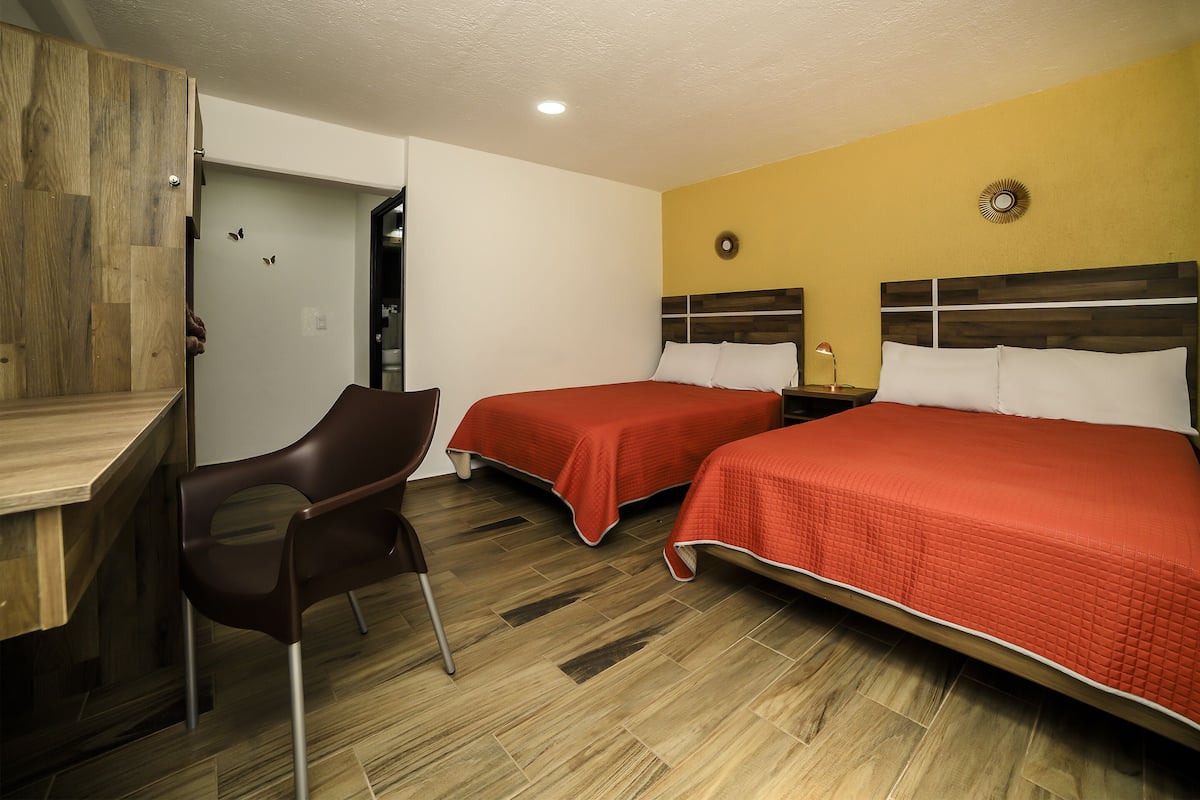 A hotel room with two beds, a desk, and a chair.