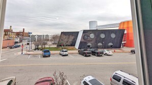 Um estacionamento com vários carros e um edifício de fachada geométrica singular.