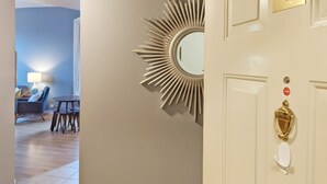 Entrada a una habitación de hotel con puerta número 6, un espejo con diseño de sol y un timbre de detalles dorados.