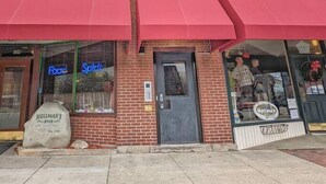 A row of brick buildings with storefronts, including a shoe store and a restaurant. - Tanner Bldg Apt 5 - Studio (Downtown) (Bay City)