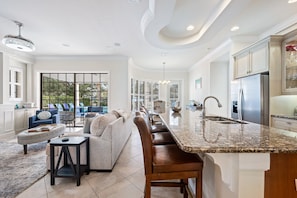 A spacious kitchen with a large island, a dining area with a sofa, and a view of the outdoors. - Reunion Luxury Home, PrivatePool/Spa, on Golf Course; 6 miles from Disney! (Reunion)