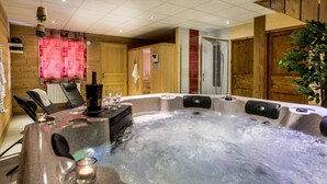 A hot tub with a bottle of champagne and glasses, surrounded by wooden walls and a cozy interior. - Chalet Snow Dream in le Bettaix (Les Belleville)