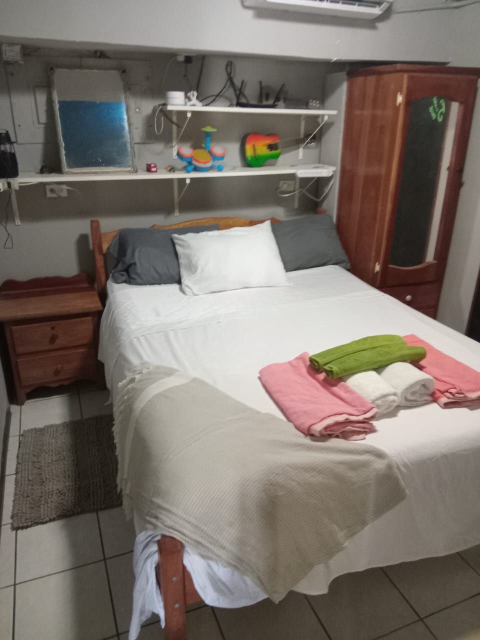Une chambre à coucher avec un lit, une table de chevet, une armoire et une étagère remplie de jouets.