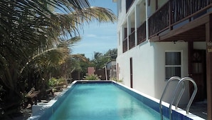 Une piscine avec un escalier en métal, entourée d’un bâtiment blanc doté de balcons.