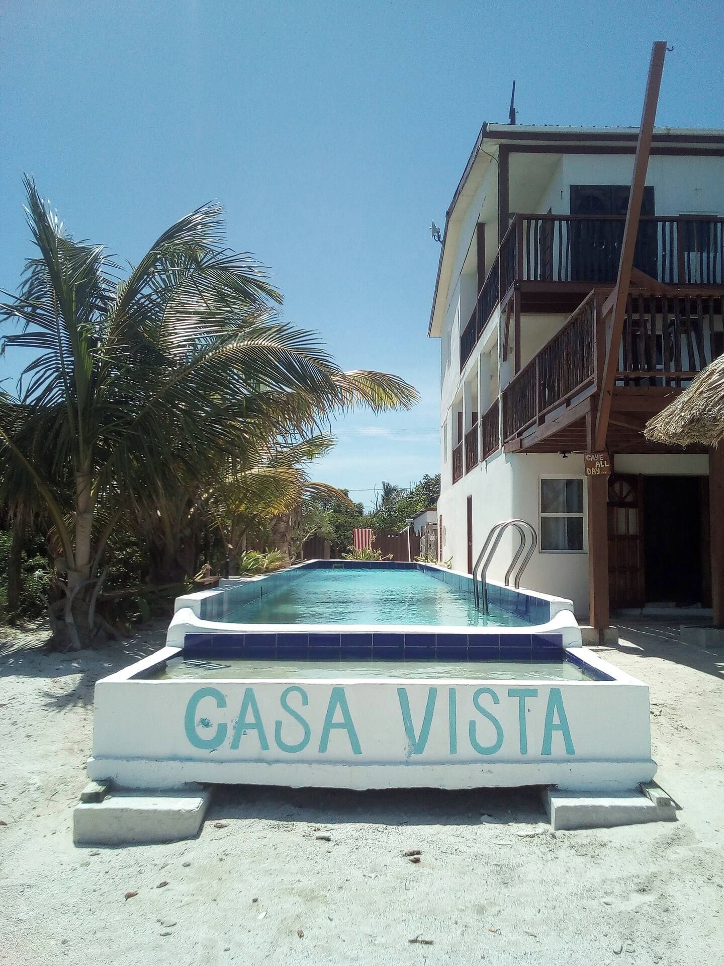 A swimming pool labeled 'GASA VISTA' on a sandy beach with a building in the background.