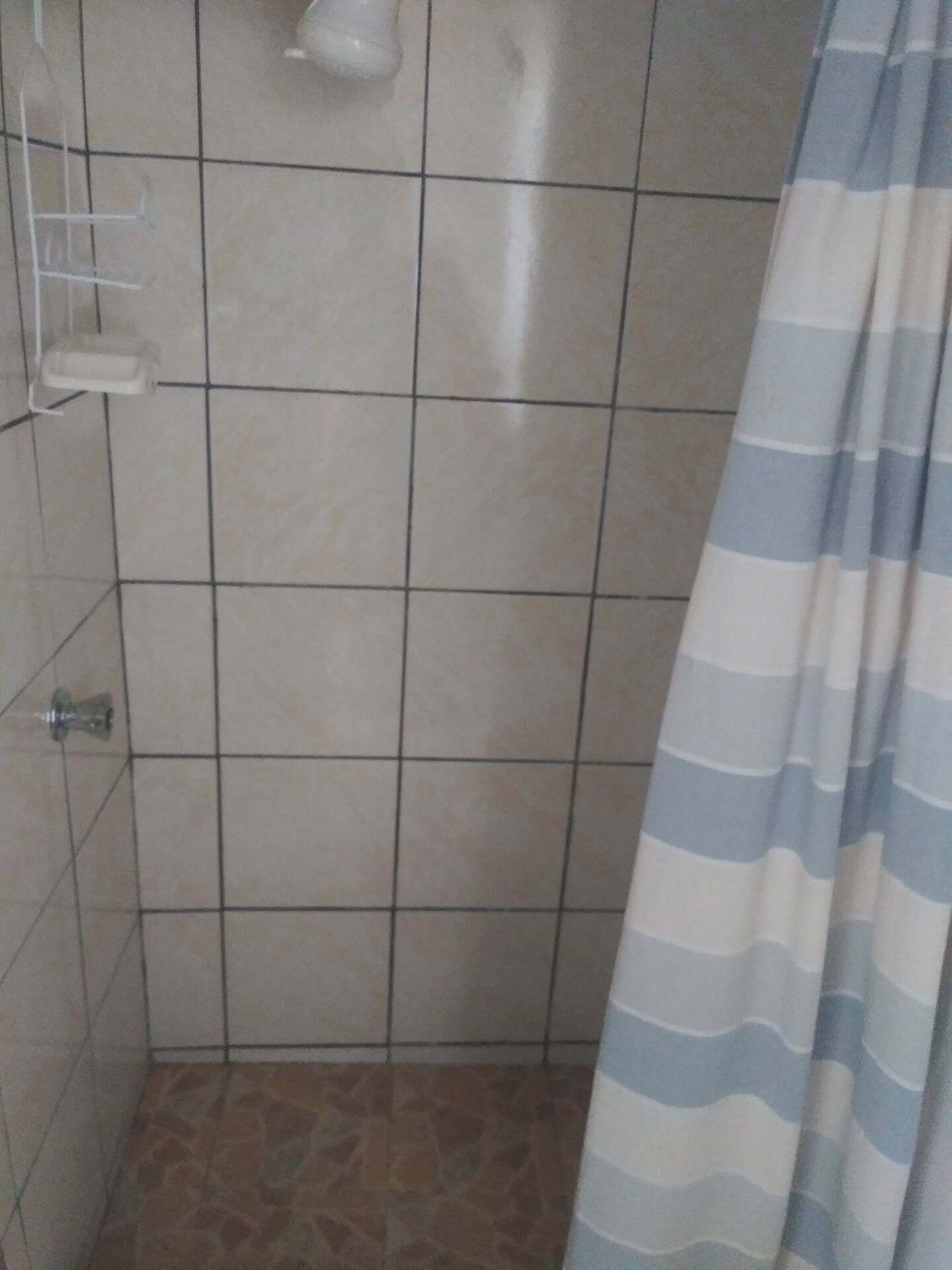 Ein gefliester Duschbereich mit einer Duschvorhang.