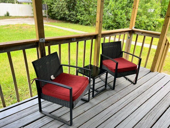 Deux chaises en osier avec des coussins rouges sur une terrasse en bois.