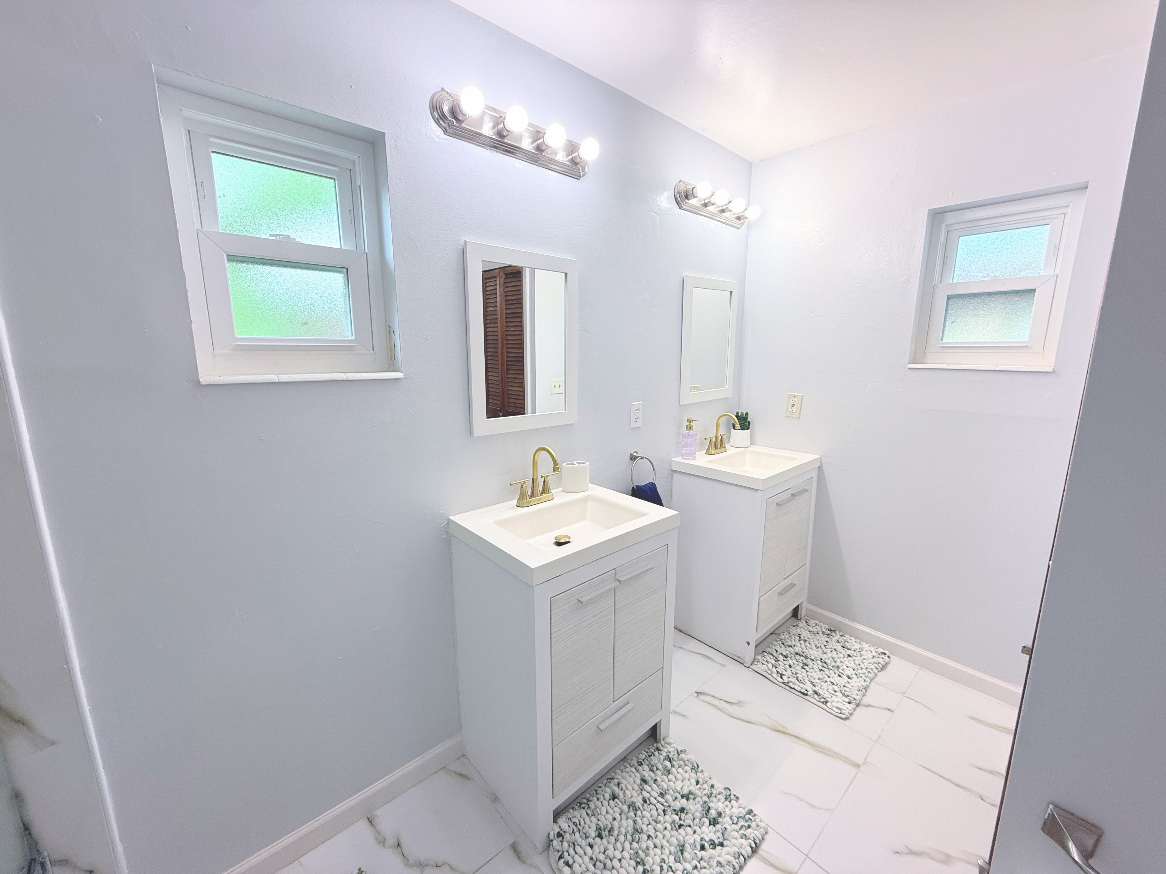 A bathroom with two sinks, a mirror, and a window.
