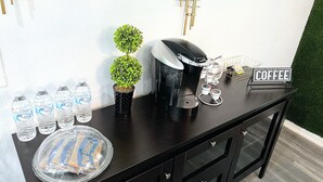 A coffee station with a Keurig machine, water bottles, a small potted plant, and a sign that says "COFFEE".