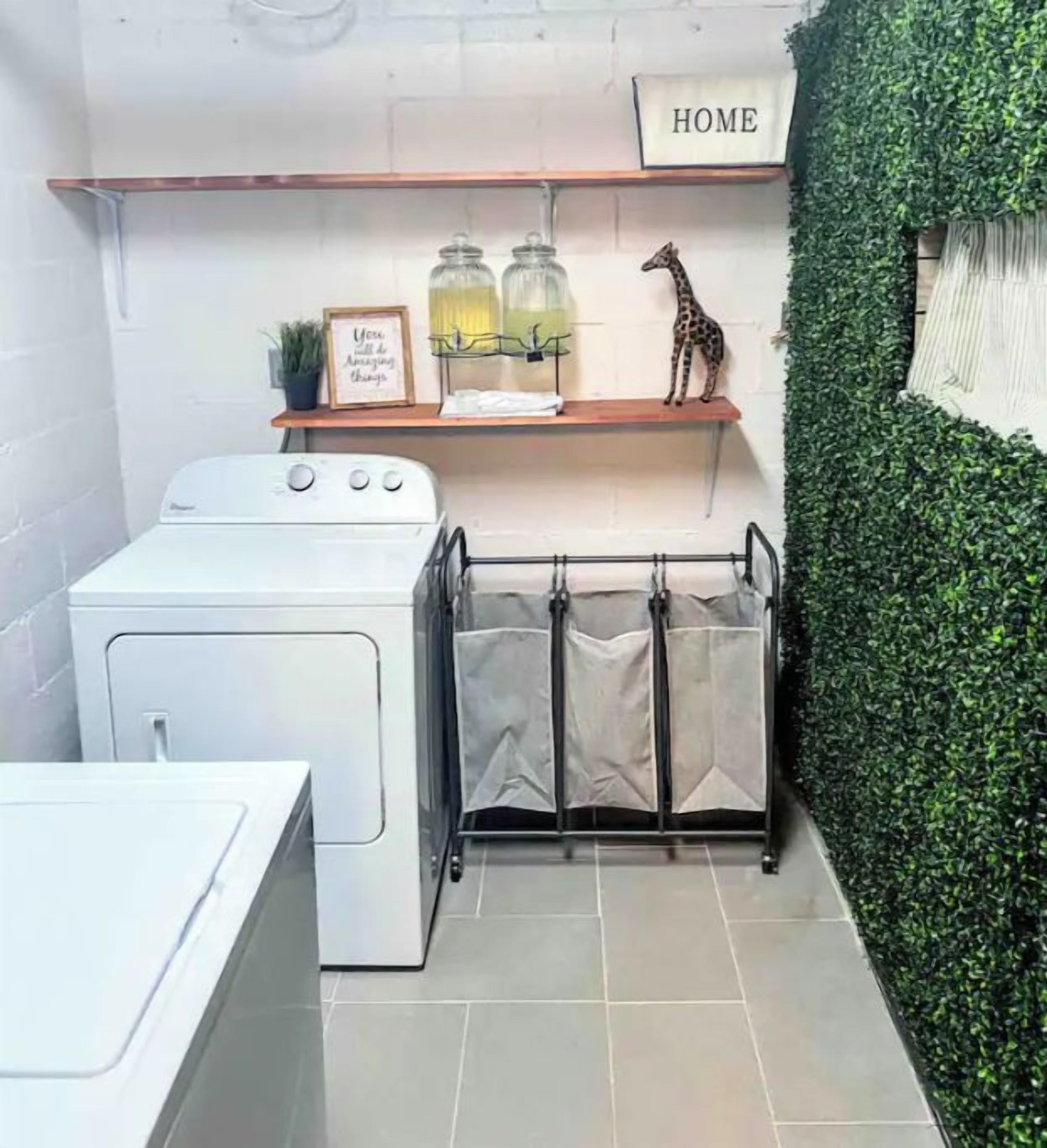 A compact laundry area with a washing machine, a drying rack, and a shelf with jars and a giraffe decoration.
