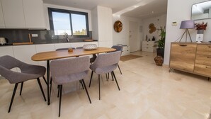Een moderne keuken met een eethoek, met een houten tafel, grijs gestoffeerde stoelen en een groot raam.