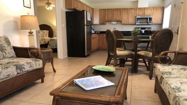 Una sala de estar con un sofá, una mesa de centro con un libro y un comedor con sillas y una mesa.