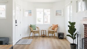 Une pièce lumineuse, avec deux fauteuils en osier, une petite table et une plante en pot.