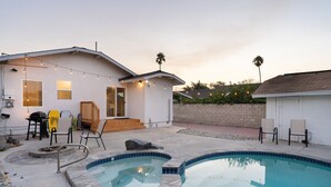 Un jardin avec une piscine, un espace barbecue et un coin salon extérieur.