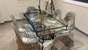A dining area with a glass-top table, patterned chairs, a potted orchid, and a tripod lamp. - House "LE CH'TI DODO (Guarbecque)