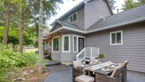A house with a covered patio area featuring a dining table and chairs, surrounded by trees. - Crystal Bay Home w/ Fireplace Near Ski Resorts (Post Falls)