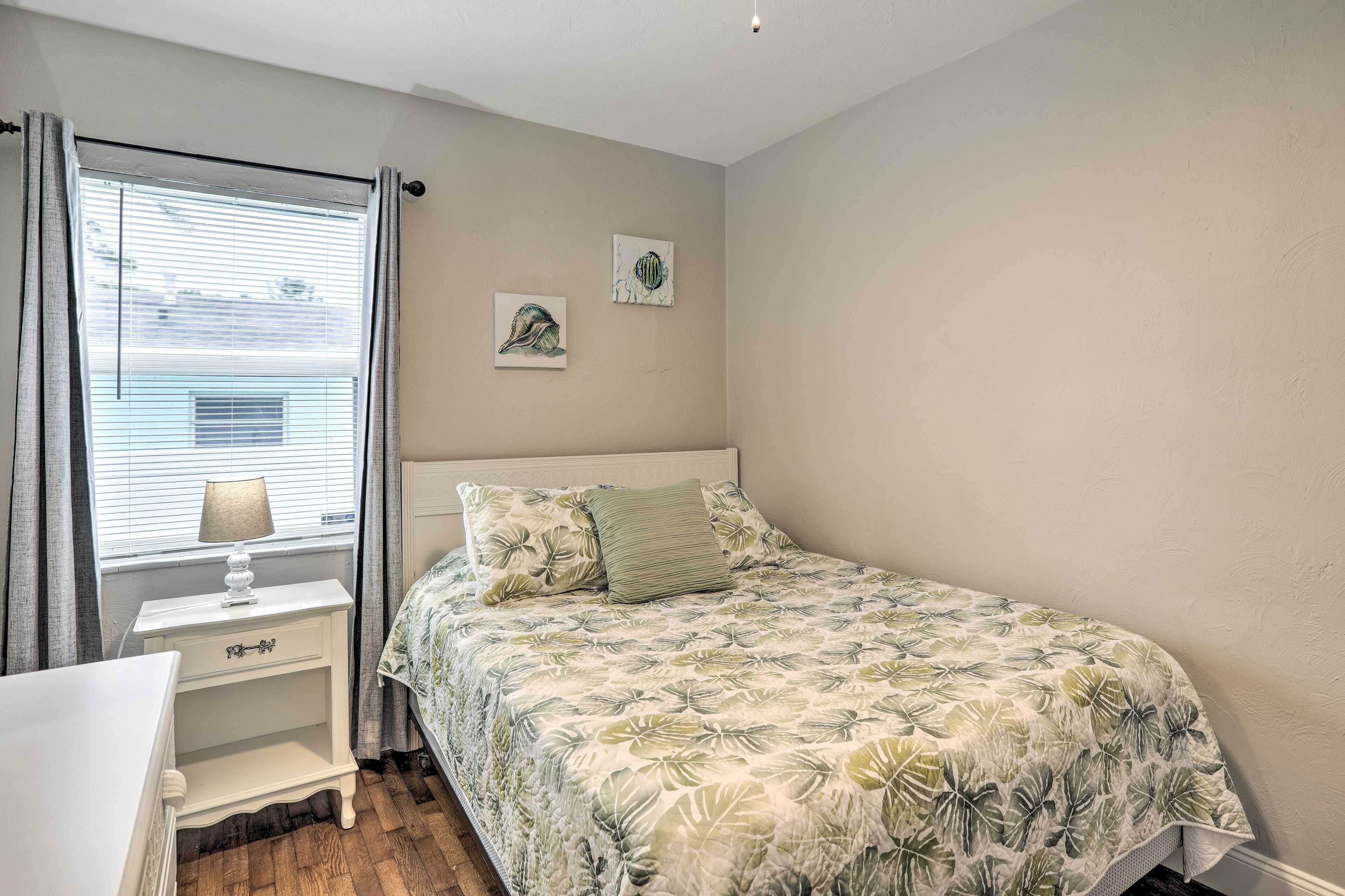 Un dormitorio con una cama, una mesita de noche, una lámpara y dos cuadros en la pared.