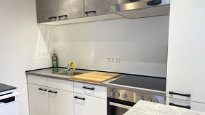Une cuisine moderne avec des meubles blancs, une hotte en acier inoxydable et un four encastré.