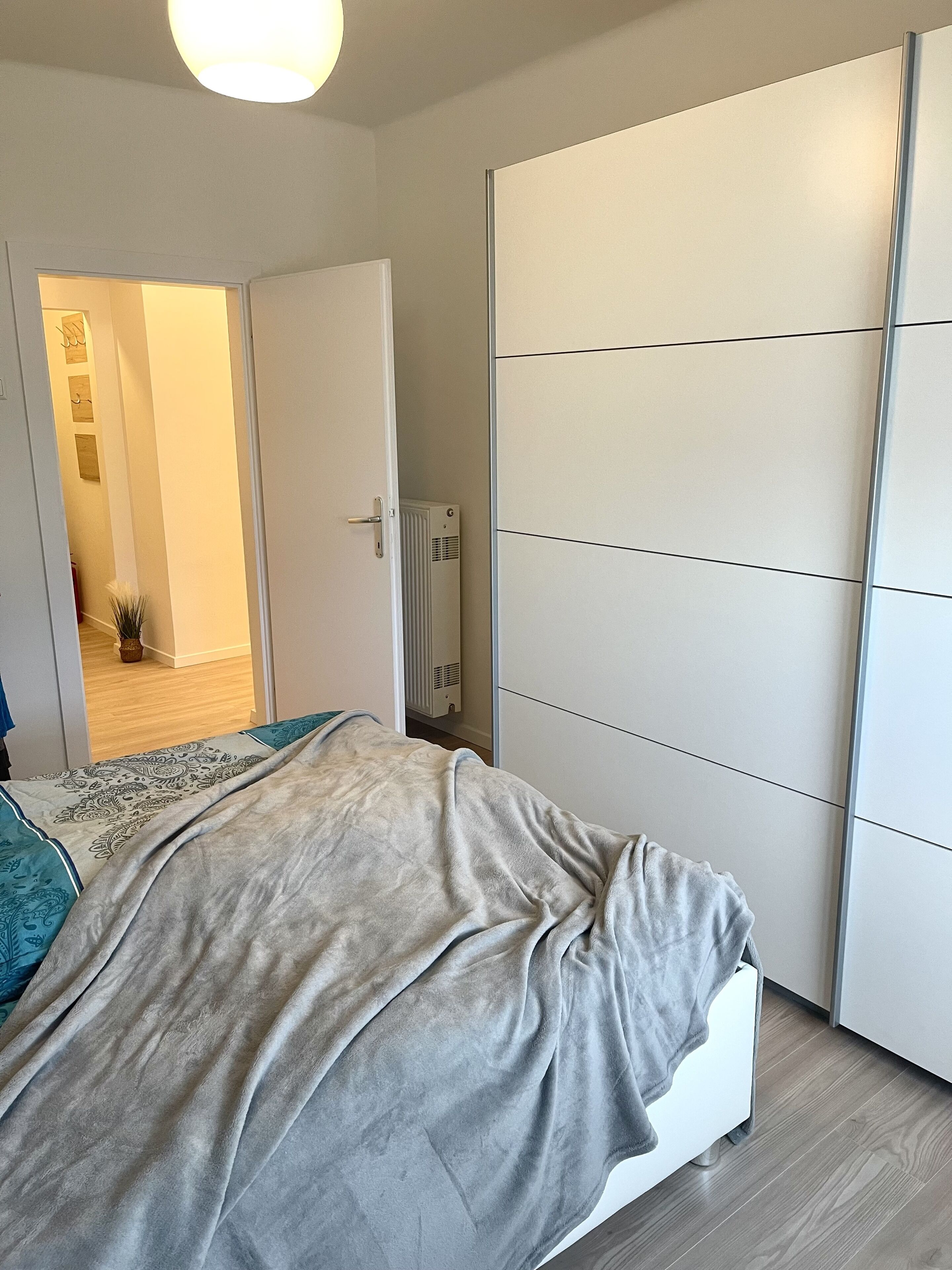 A bedroom with a bed, a wardrobe, and a radiator.