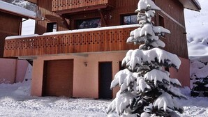 Una cabaña de madera con balcón, rodeada de montañas nevadas.