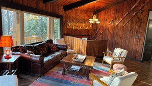 A cozy cabin interior with a leather sofa, a wooden coffee table, and a patterned rug. - Unique Octagon Ski Lodge in heart of Rib Mountain State Park with hot tub (Wausau)