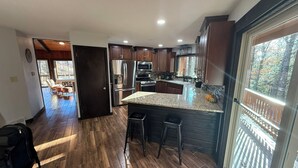 A modern kitchen with dark wood cabinets, stainless steel appliances, and a large island with stools. - Unique Octagon Ski Lodge in heart of Rib Mountain State Park with hot tub (Wausau)
