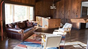 A wooden interior with a leather sofa, a white armchair, and a dining area. - Unique Octagon Ski Lodge in heart of Rib Mountain State Park with hot tub (Wausau)