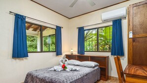 Ein Schlafzimmer mit Bett, Nachttisch, Stuhl und einem Fenster mit Vorhängen.