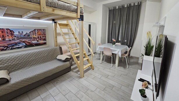 A room with a bunk bed, a sofa, a dining table with chairs, a TV, and a plant. - Cozy apartment very close to metro and bus to visit Rome (Roma)