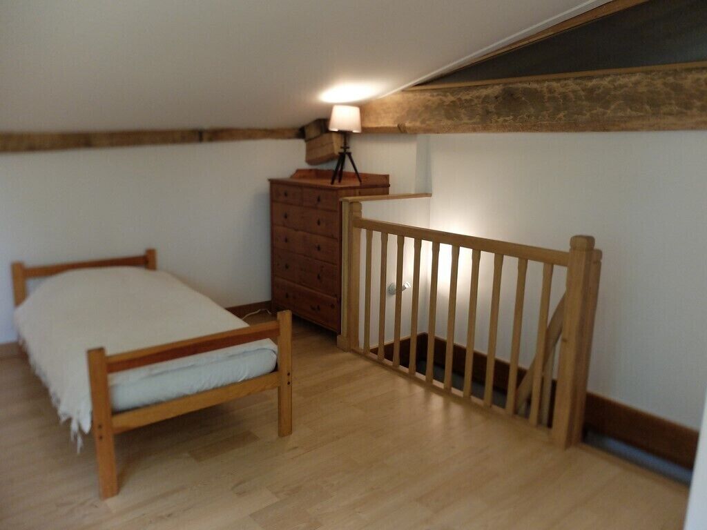 A bedroom with a wooden bed, a dresser, and a small desk with a lamp.