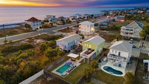 A coastal residential area with houses, a swimming pool, and a view of the ocean at sunset. - Luxe Coastal Dream w/Ocean Views + Private Pool (Port St. Joe)