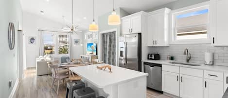 Una cocina moderna con armarios blancos, electrodomésticos de acero inoxidable y una isla grande con taburetes de bar.