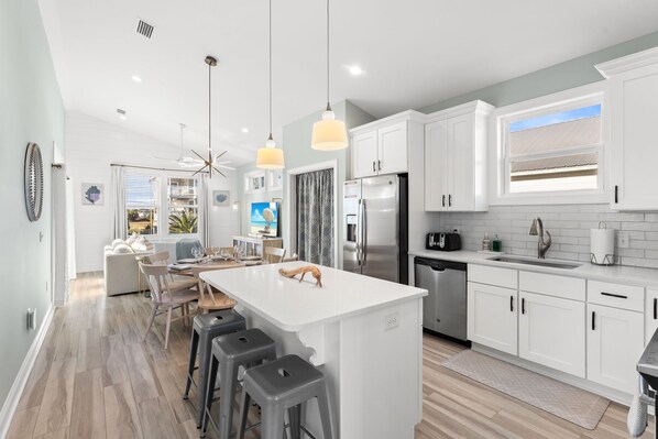A modern kitchen with white cabinets, stainless steel appliances, and a large island with bar stools.