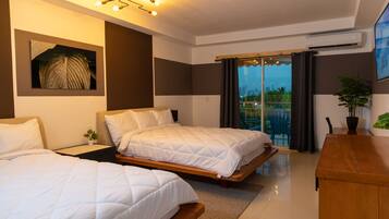 A modern hotel room with two beds, a wooden desk, a large window with curtains, and a city view.