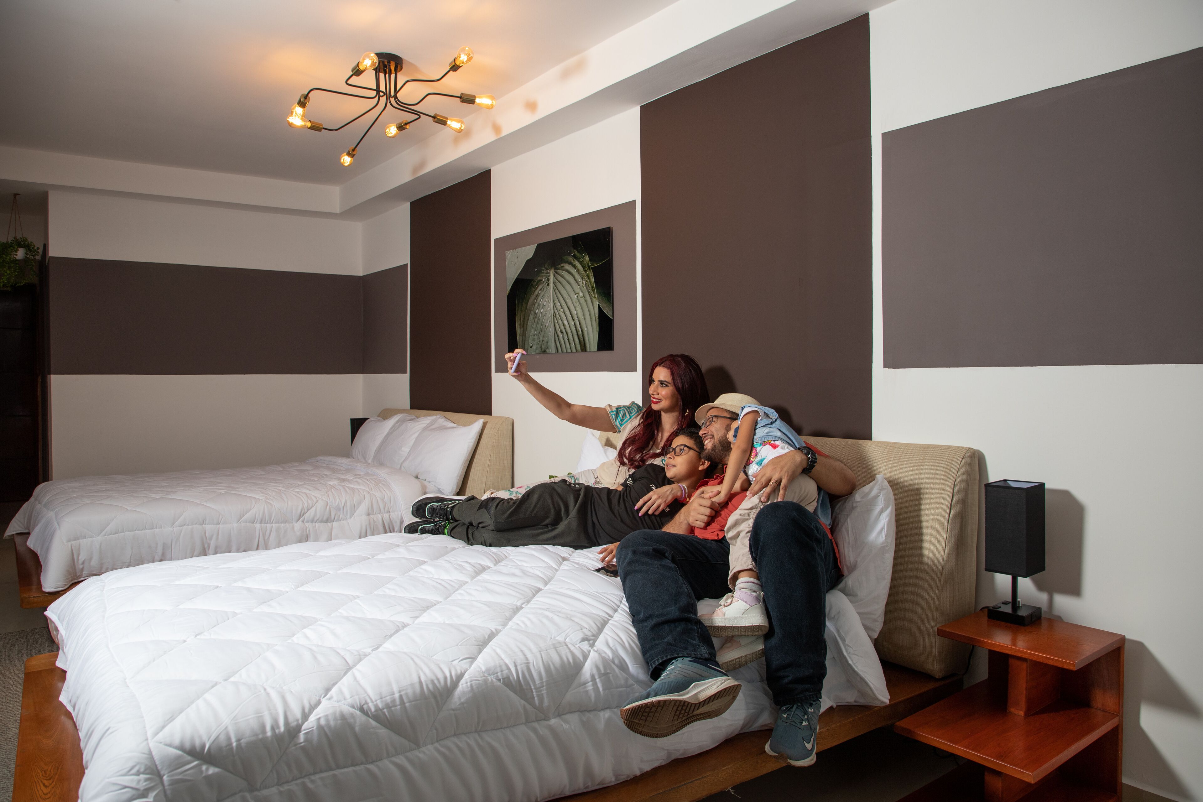 Ein Schlafzimmer mit zwei Betten, einer modernen Kronleuchter und einem Nachttisch mit Lampe.