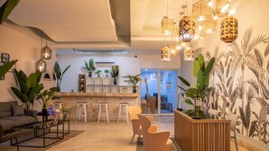 A modern interior with a reception desk, seating area, and potted plants. - MARINN Tropical Vibes Hotel (Panama City)